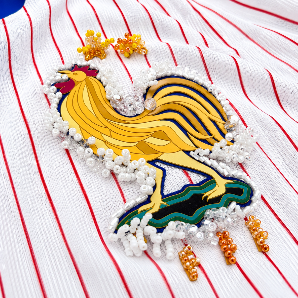 Maillot de football bleu,blanc,rouge upcyclé OHBAB à lignes bleues et rouges, avec fronces, volant blanc sur les manches et écusson brodé de perlescolorées.