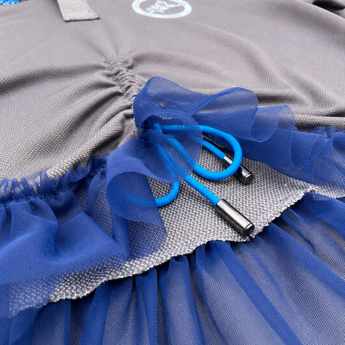 Détail de la fronce centrale et du cordon bleu électrique avec embouts métalliques.