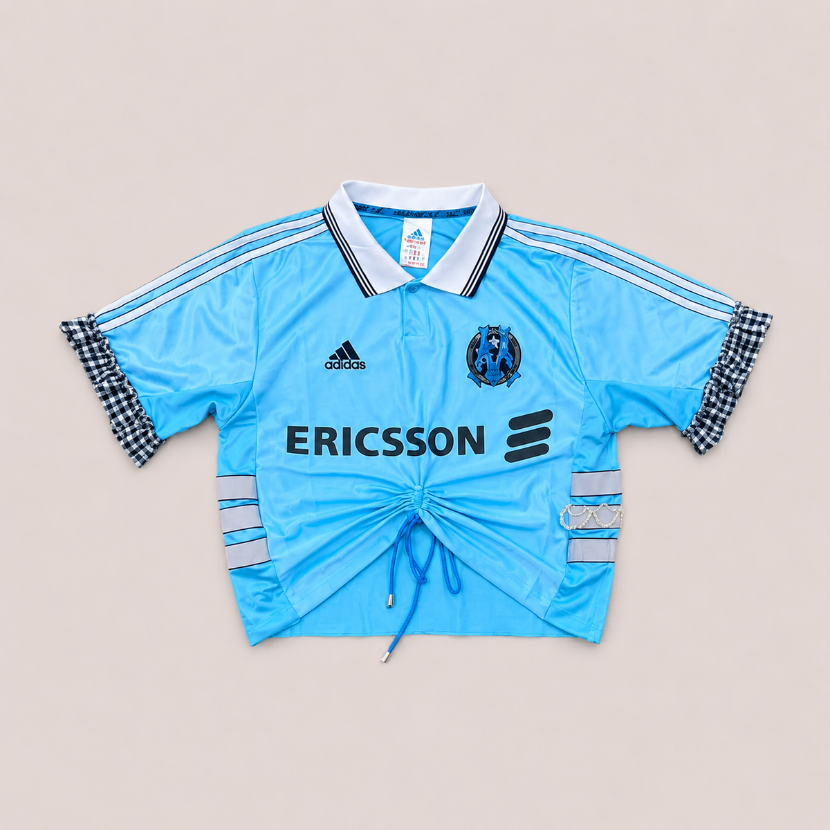 Maillot de foot bleu ciel de seconde main transformé à la main à Bayonne avec volants argentés et broderies de perles. Pièce unique OHBAB.
