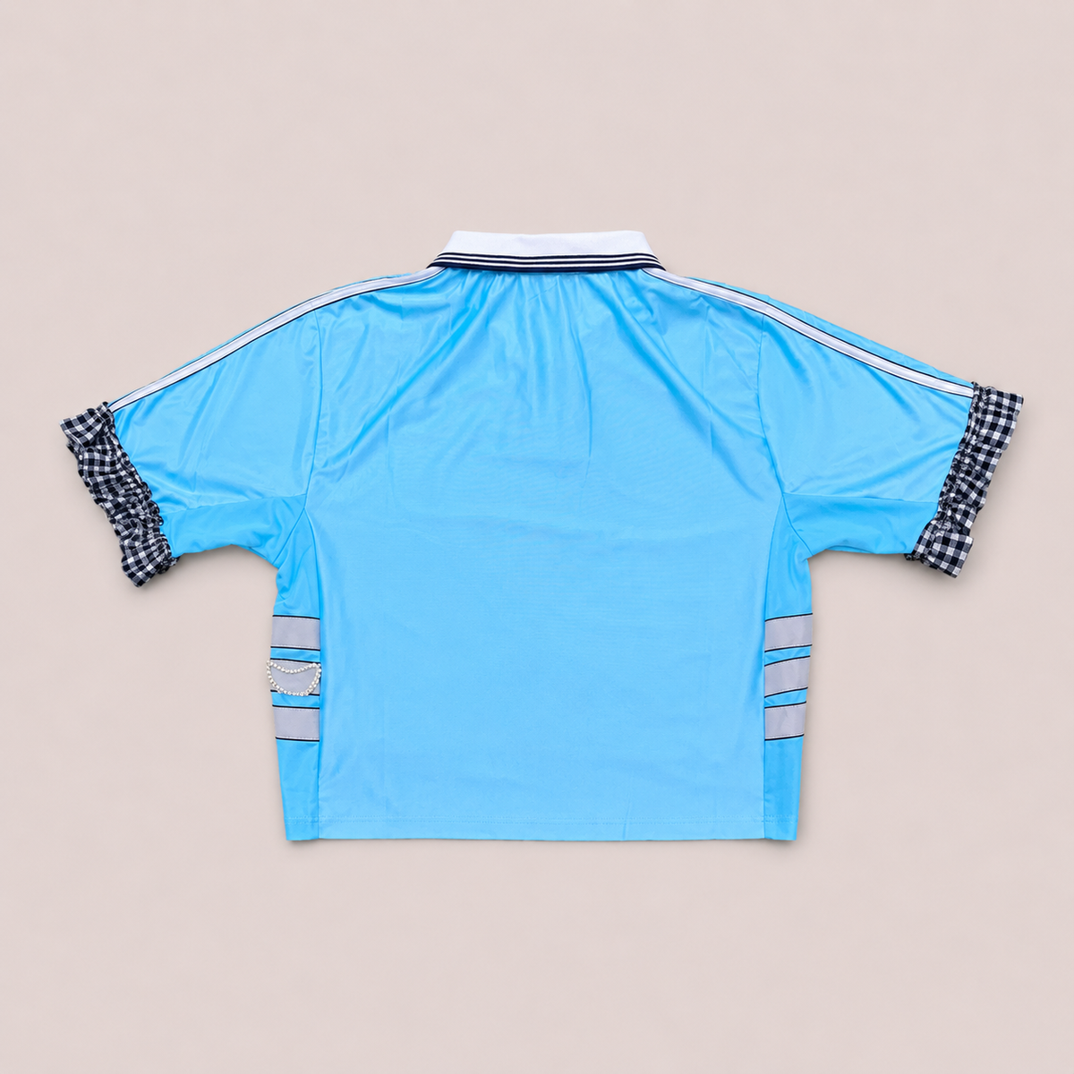 Maillot de foot bleu ciel de seconde main transformé à la main à Bayonne avec volants argentés et broderies de perles. Pièce unique OHBAB.