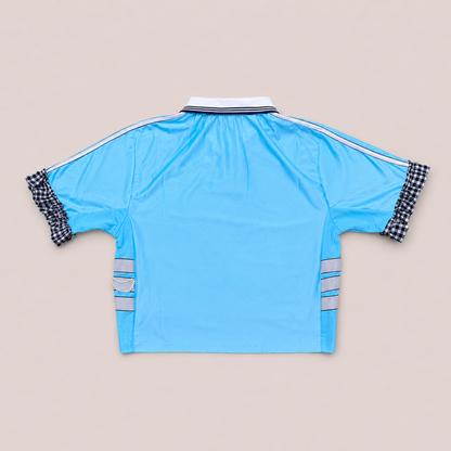 Maillot de foot bleu ciel de seconde main transformé à la main à Bayonne avec volants argentés et broderies de perles. Pièce unique OHBAB.