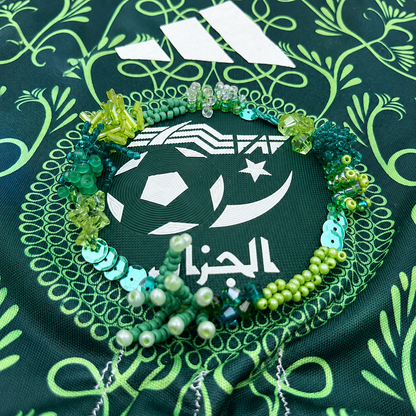 Détail des perles vertes et turquoise brodées à la main autour de l’écusson du maillot.