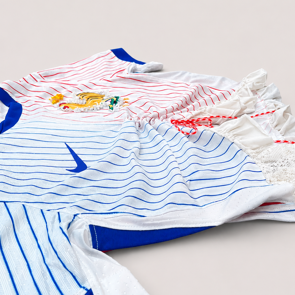 Maillot de football bleu,blanc,rouge upcyclé OHBAB à lignes bleues et rouges, avec fronces, volant blanc sur les manches et écusson brodé de perlescolorées.