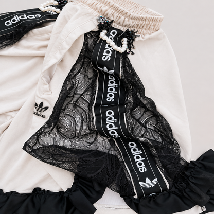 Short de football blanc transformé à la main à Bayonne avec dentelle noire, volants et perles reliant le devant au dos. Pièce unique OHBAB.