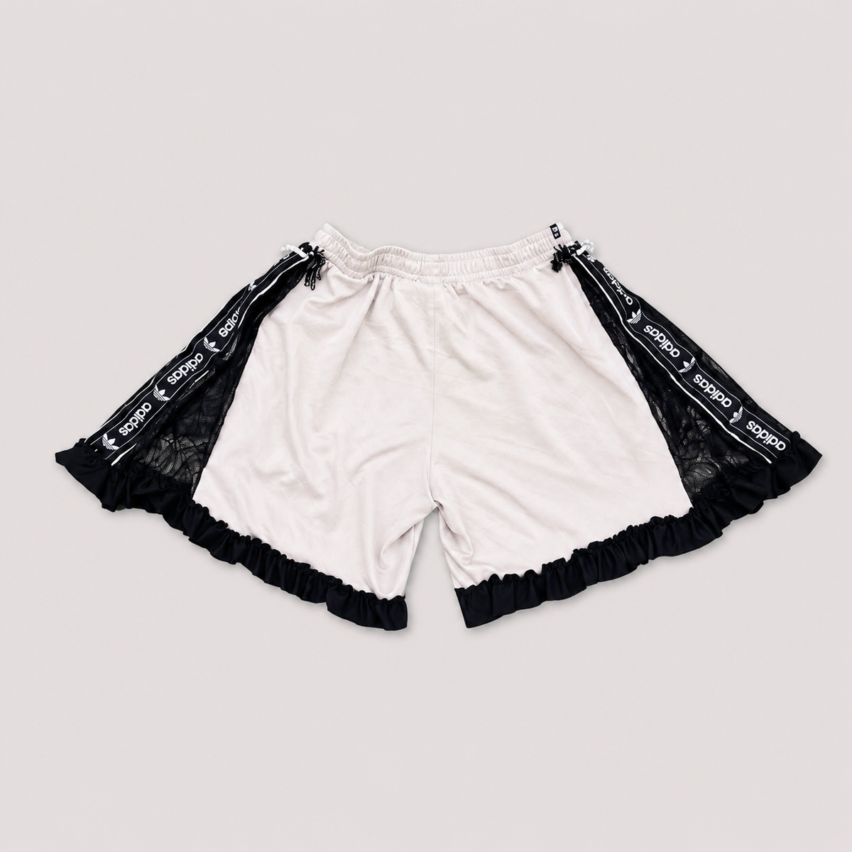 Short de football blanc transformé à la main à Bayonne avec dentelle noire, volants et perles reliant le devant au dos. Pièce unique OHBAB.
